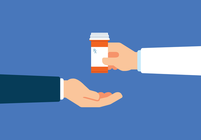 hand in doctor clothing handing pill bottle to another hand