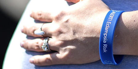 A pregnant woman wearing a rubber blue wrist band that says Alert Eclampsia Risk