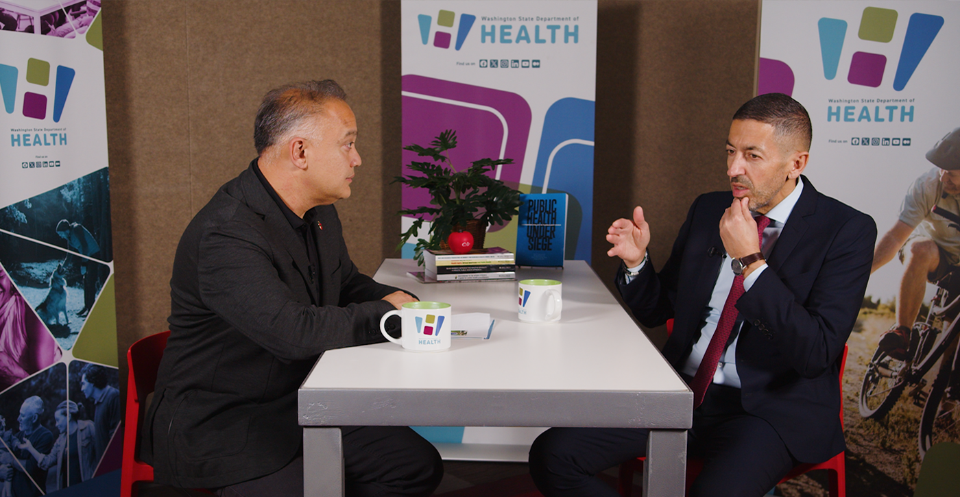 Dr. Umair Shah and Sandro Galea talking at a table.