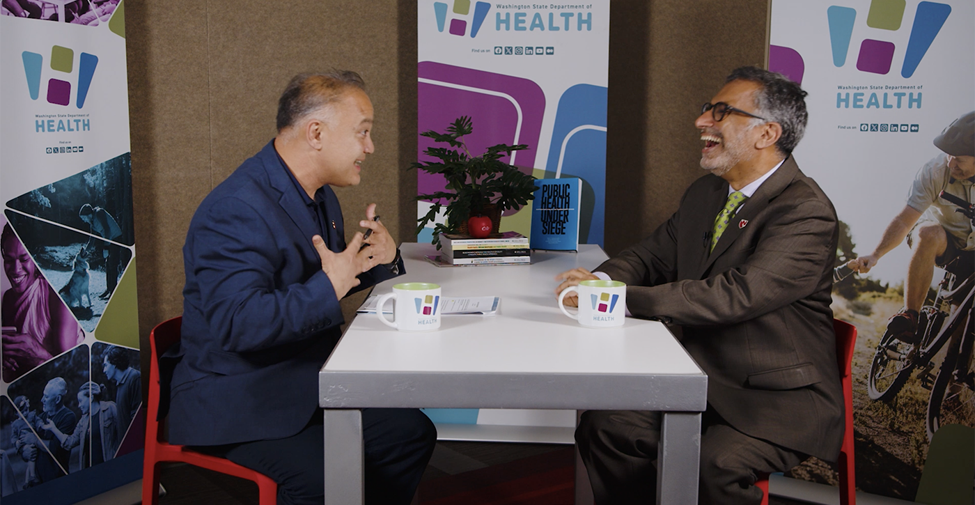 Dr. Umair Shah and Dr. Ali S. Khan talking at a table.