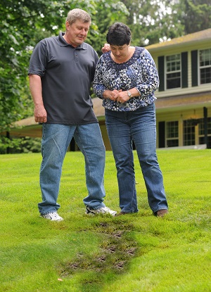 Man and women looking at soggy grass which may indicate a failing septic system.
