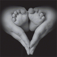 Picture of a mothers hands holding a babies feet in the shape of a heart.