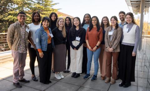 A group of 13 students pose for a photo while standing together outside.