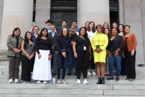 About 20 people pose for a photo on the steps of the Legislative Building.