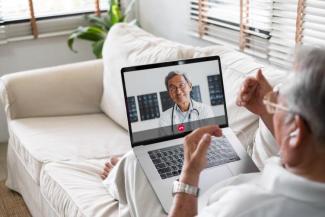 A patient talks to a physician on their laptop at home